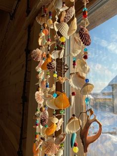 a wind chime hanging from the side of a window with seashells on it