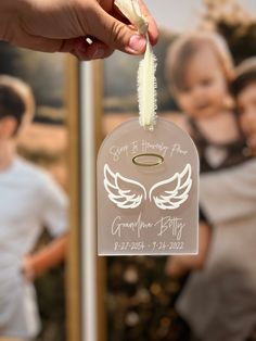 a person holding up a tag with an angel on it and two children in the background