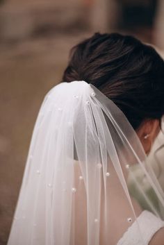 the back of a bride's head wearing a white veil and pearls on it