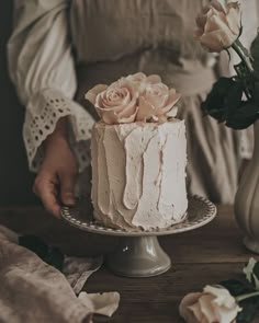 a woman is holding a cake with flowers on the top and frosting in the middle