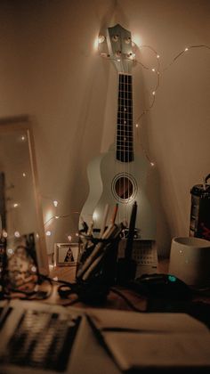 a guitar sitting on top of a desk next to a laptop computer and other items