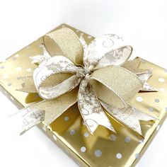 a gold gift box with a white polka dot bow