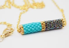 a gold chain with a blue beaded tube on it's end and a yellow chain attached to it