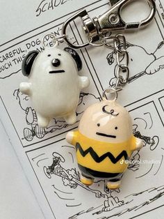 two cartoon key chains are sitting on top of a piece of paper that is next to each other