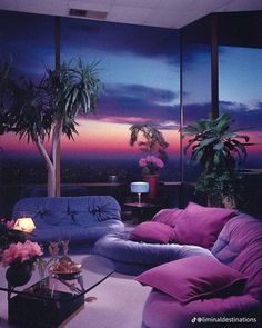 a living room filled with purple couches and potted plants on top of a table