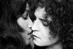 black and white photograph of two women with curly hair, one kissing the other's forehead