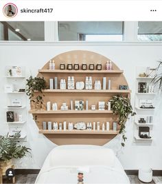 a white bed sitting in a bedroom next to a wooden shelf filled with books and plants