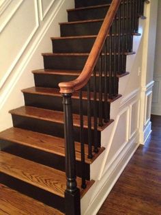 an image of a stair case with wood handrails and black painted railing on the bottom