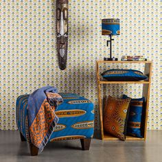 a bedroom with blue and orange bedspread, wooden shelving unit and decorative wallpaper