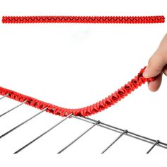 a hand holding a red string attached to an oven grate on a white background