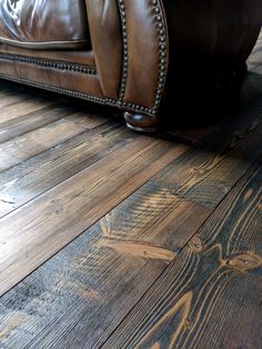 a brown leather couch sitting on top of a wooden floor