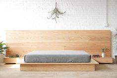 a bed sitting on top of a wooden platform in a bedroom next to potted plants