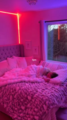 a girl is sleeping on her bed in the middle of the room with pink lights