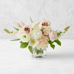 a vase filled with white and pink flowers on top of a marble countertop next to a wall