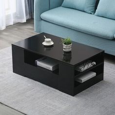 a black coffee table sitting on top of a rug in front of a blue couch