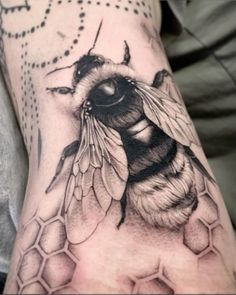 a black and white tattoo of a bee on the arm