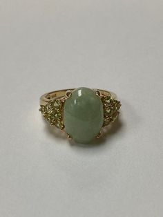 Lady's 14 karat yellow gold ring, with a large oval green jadeite jade at the center and accented by 12 round full cut natural peridot gemstones. The jade measures 14.0 mm x 10.0 mm with a depth of 4.65mm. The 12 round peridot measure approximately 2.5mm each. The ring is a size 8 and can be sized up or down. The ring weighs 4.72 grams. The ring is from an estate here in Hawai'i. The item is C11870/2 Please let me know if you have an questions. Mahalo for looking at my item.