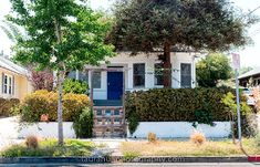 a small white house with a blue door and some bushes in front of it that says before