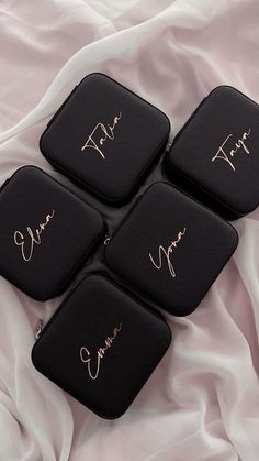 four black coasters with gold writing on them sitting on a white sheet covered bed