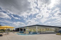 an empty swimming pool in front of a building with yellow umbrellas on the side