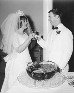 a bride and groom standing in front of a cake