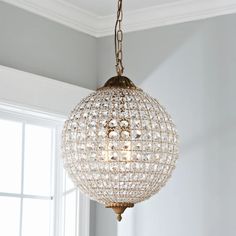 a chandelier hanging from a ceiling in a room with white walls and windows