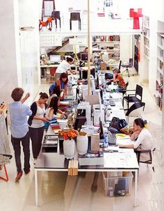 several people working in an art studio with lots of desks and chairs around them