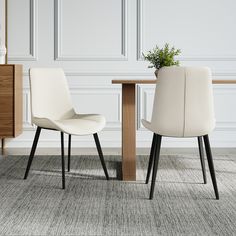 two white chairs sitting next to each other near a table with a potted plant on it