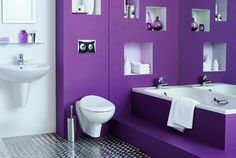 a bathroom with purple walls and white fixtures in the bathtub, toilet and sink