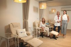 three people standing in a room with chairs