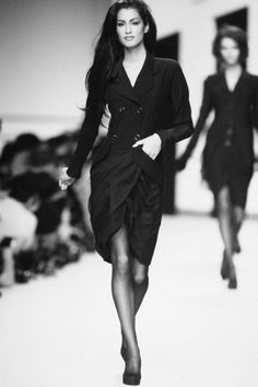 black and white photo of two women walking down the runway