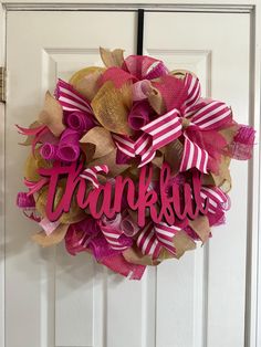 a pink and gold wreath with the word thank you on it hanging on a door