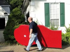 a man walking past a giant red heart shaped object