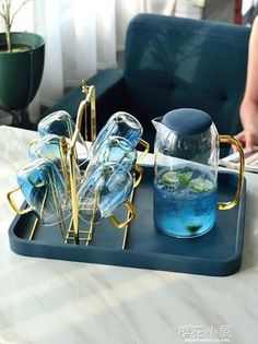 there is a tray with glasses and lemons on it next to a blue couch