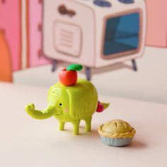 an elephant figurine standing next to a cupcake on a table in front of a microwave