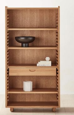 a wooden bookcase with two drawers and a bowl on top of the bookshelf