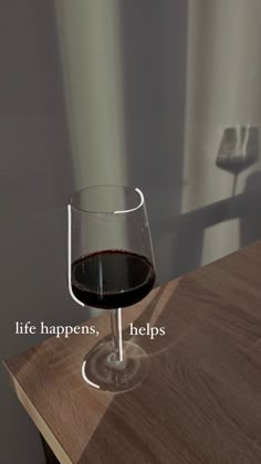 a glass of wine sitting on top of a wooden table