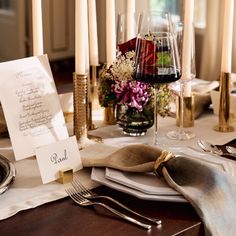 a table set with place cards, silverware and candles