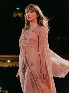 a woman in a pink dress is walking down the runway