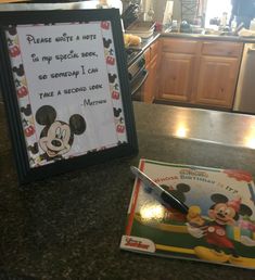 a mickey mouse birthday card and pen on a kitchen counter with a framed sign that says please write a letter to my special son so somebody i can take a second look at