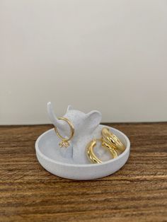 two gold rings sitting in a bowl on a wooden table