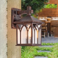 an outdoor light hanging from the side of a wall next to a table and chairs