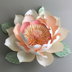 a large paper flower with leaves on the top and bottom is hanging from a wall