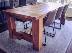 a wooden table with chairs around it in a living room next to a large window