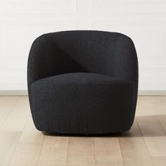 a black chair sitting on top of a hard wood floor next to a white wall