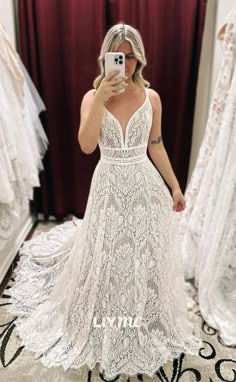 a woman taking a selfie in front of her wedding dress and looking into the mirror