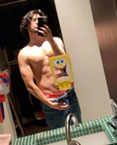 a shirtless man takes a selfie in the mirror with his cell phone and spongebob towel