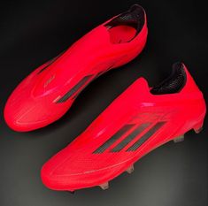 a pair of red soccer shoes on a black surface