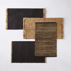 four woven rugs in different colors and patterns on a white surface with one black, the other brown