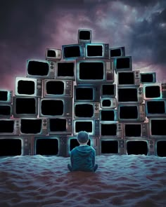 a man sitting on the ground in front of stacks of television's and watching them